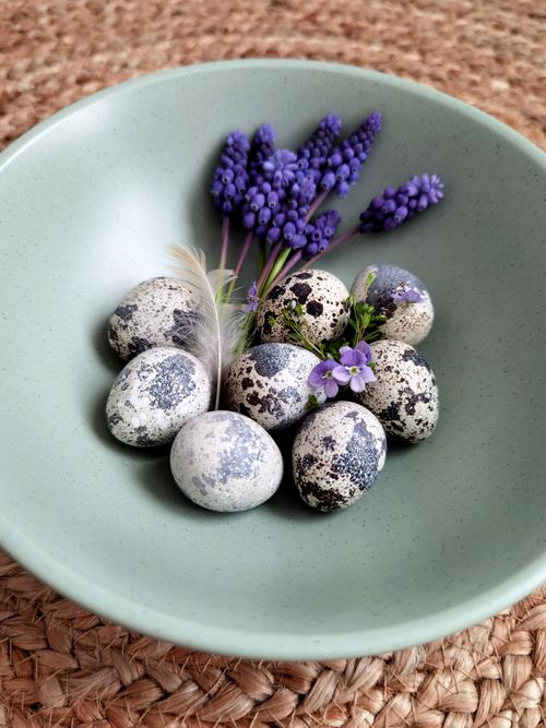 Free Artistic arrangement of quail eggs and lavender in a green ceramic bowl. Stock Photo