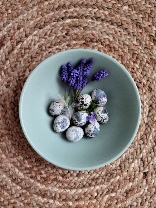 Free Top view of quail eggs and lavender in a mint green bowl on a woven placemat. Stock Photo