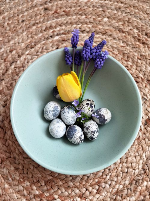 Free A serene still life of quail eggs and spring flowers in a ceramic bowl. Stock Photo