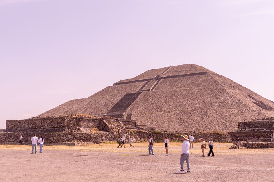 Visitors explore the Pyramid of the Sun at Teotihuacan under a clear sky.