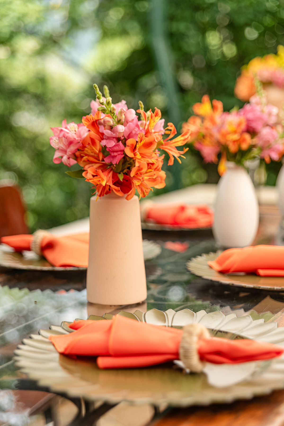 Vibrant outdoor table setting with orange floral arrangements and elegant place settings. Stock Photo.