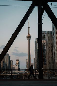 Silhouette of a person walking with the CN Tower in Toronto's skyline at dusk.