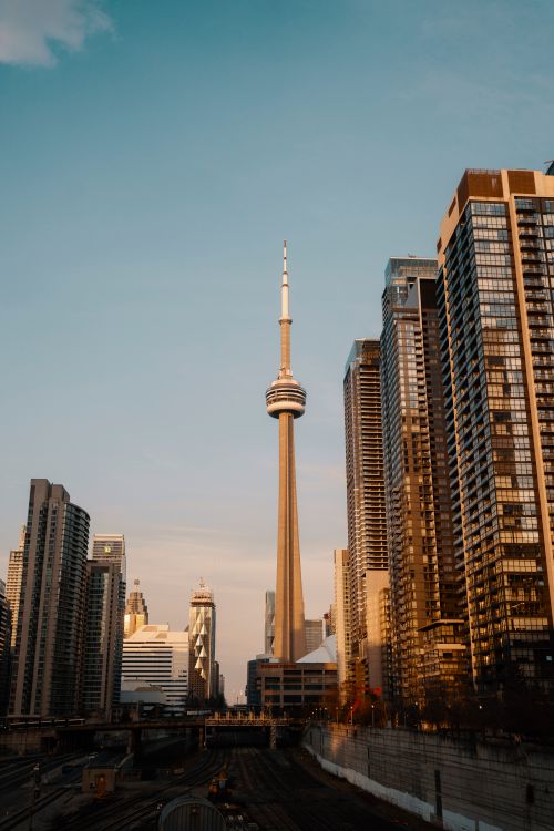Free The CN Tower amidst Toronto's modern skyline during sunset, capturing the city's iconic urban architecture. Stock Photo