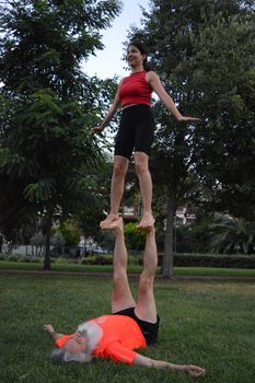 Acroyoga performance by a duo balancing on grass in Istanbul park.