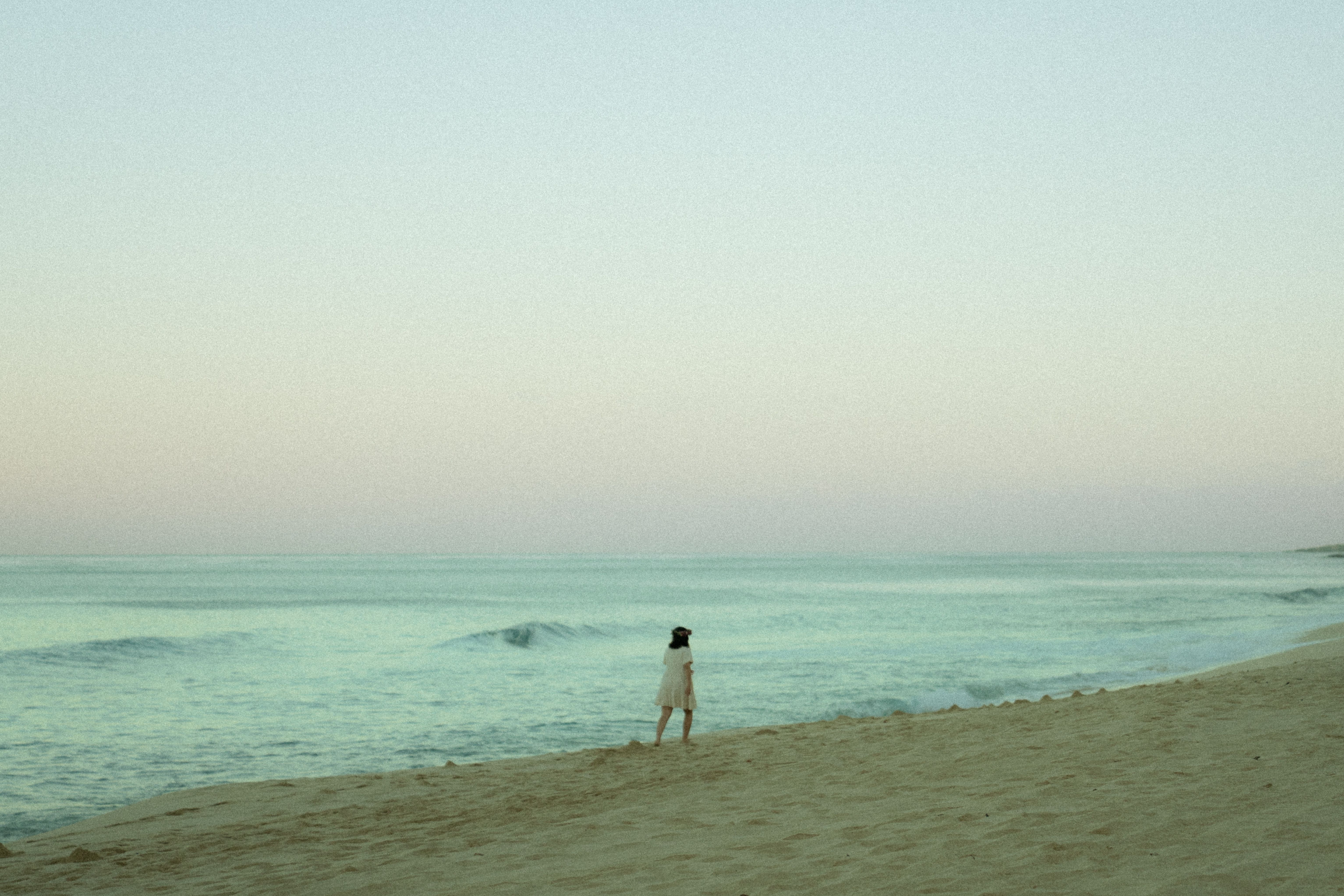 Gratis Una persona solitaria che cammina su una spiaggia tranquilla al tramonto, evocando tranquillità. Foto a disposizione