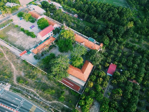 Free Aerial shot of countryside buildings with red roofs, lush greenery. Stock Photo