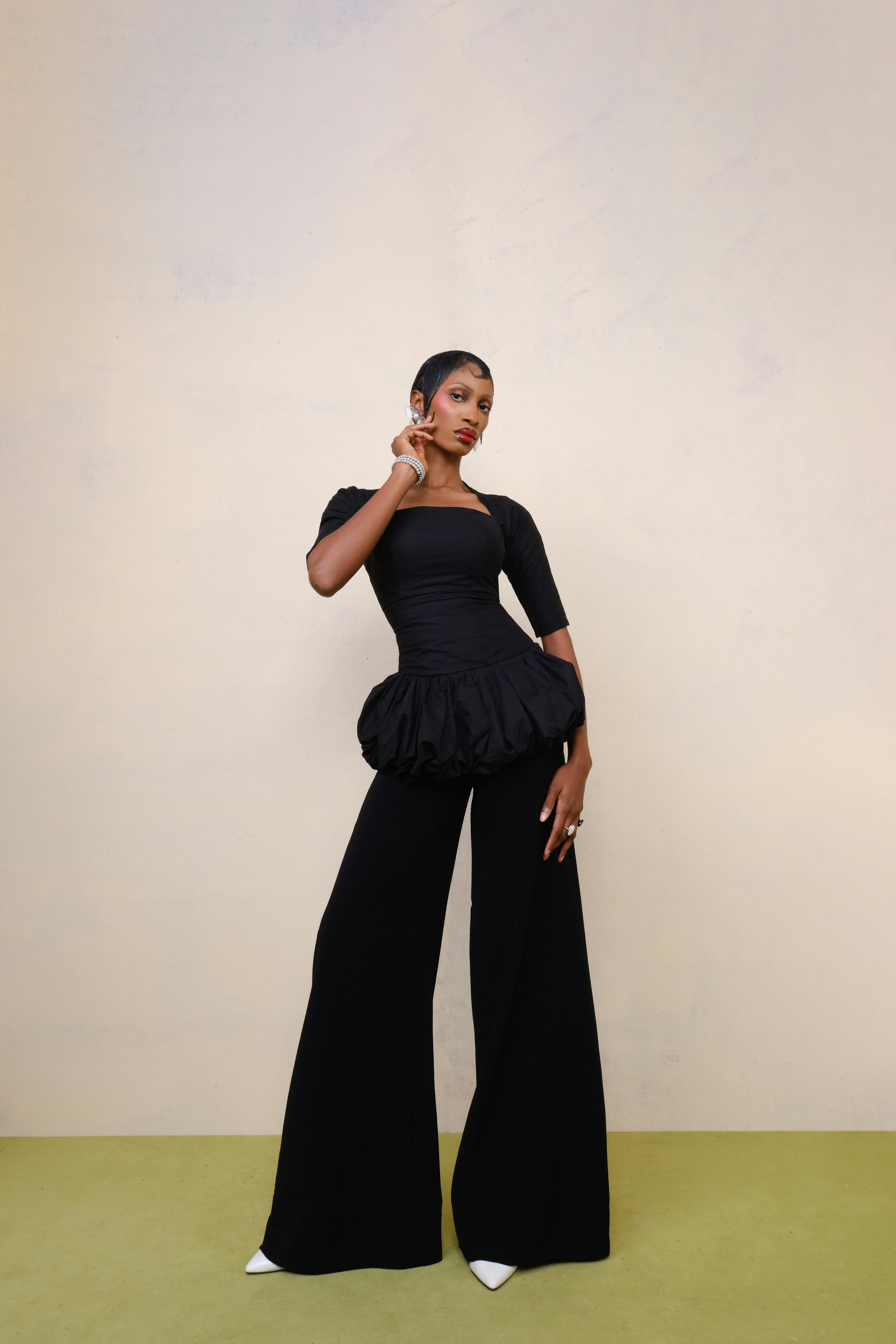 De franc Un model de moda posa elegantment amb un vestit negre amb pantalons acampanats, mostrant un estil modern. Foto d'estoc