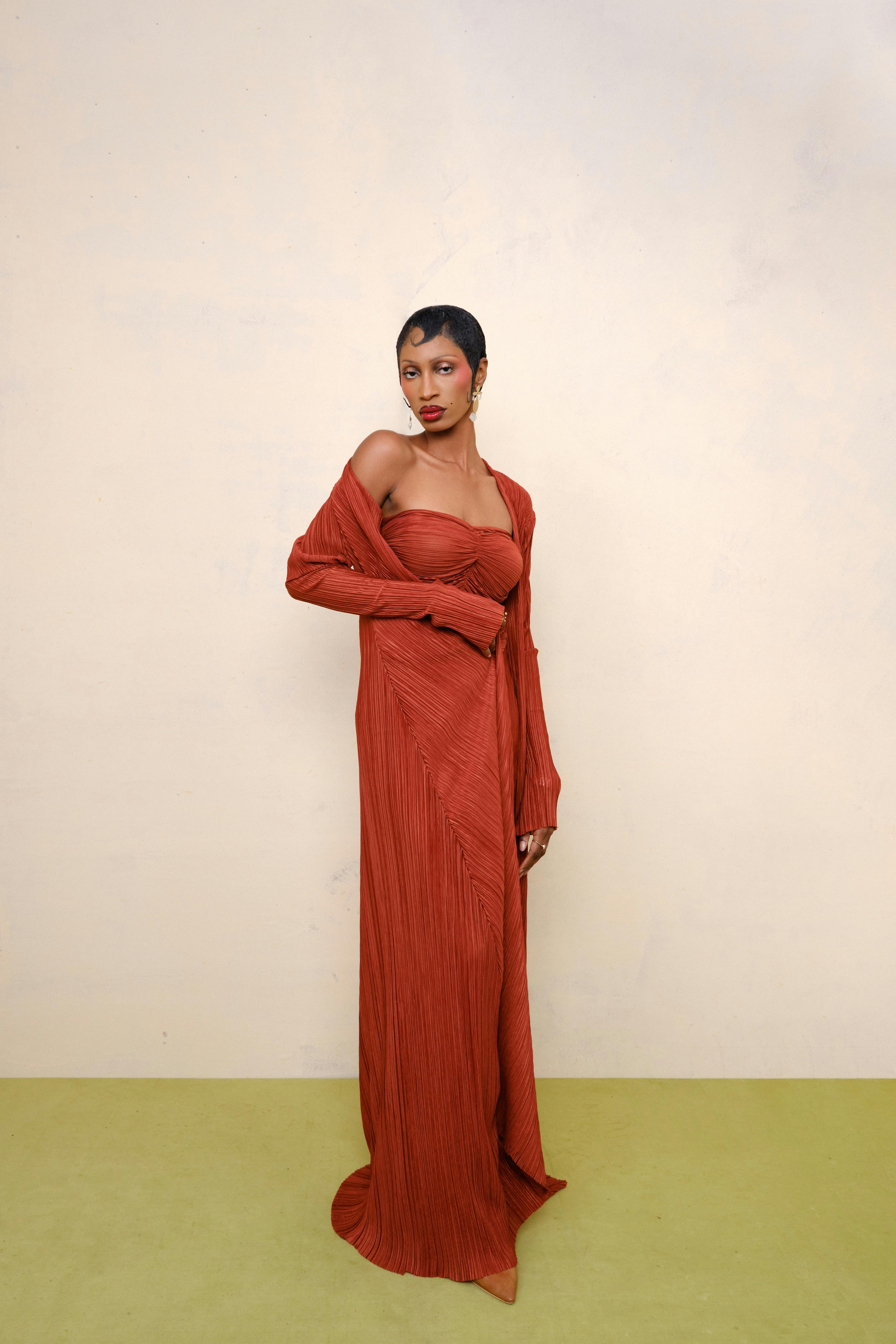 Striking portrait of a woman in a vivid red gown against a neutral backdrop.
