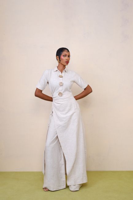 Stylish woman in white attire posing in a minimalist studio setting.
