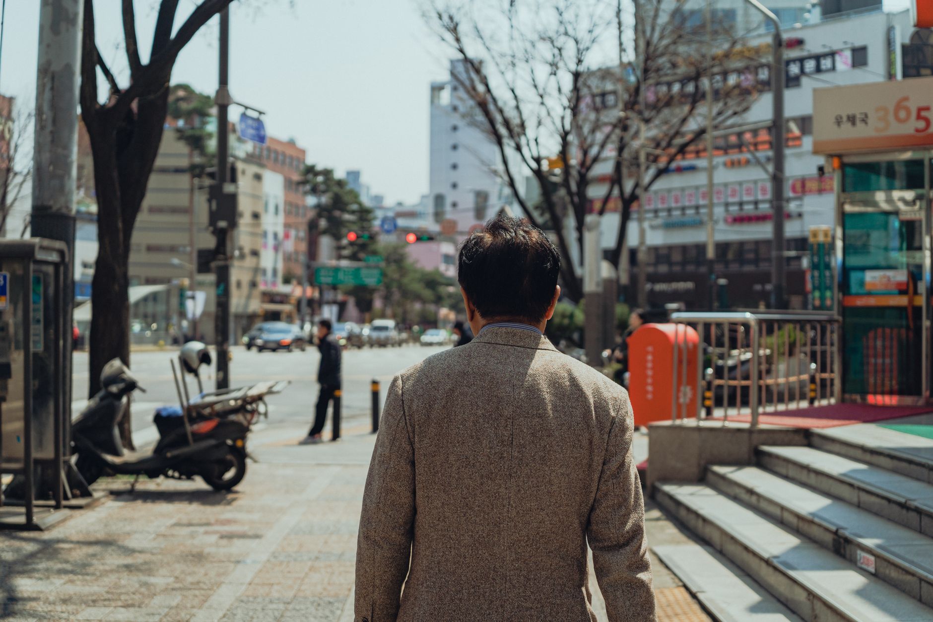 Street photography capturing a man walking in a busy Seoul street during daylight.