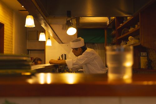 Free A Japanese chef in uniform focuses on preparing a dish in a cozy Tokyo restaurant kitchen. Stock Photo