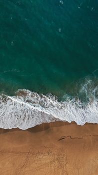 Stunning aerial view of a clear blue ocean meeting a sandy Hawaiian beach, showcasing natural beauty.