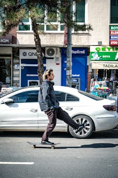 A skateboarder skating past parked cars on a sunny day in Ankara, showcasing urban lifestyle.