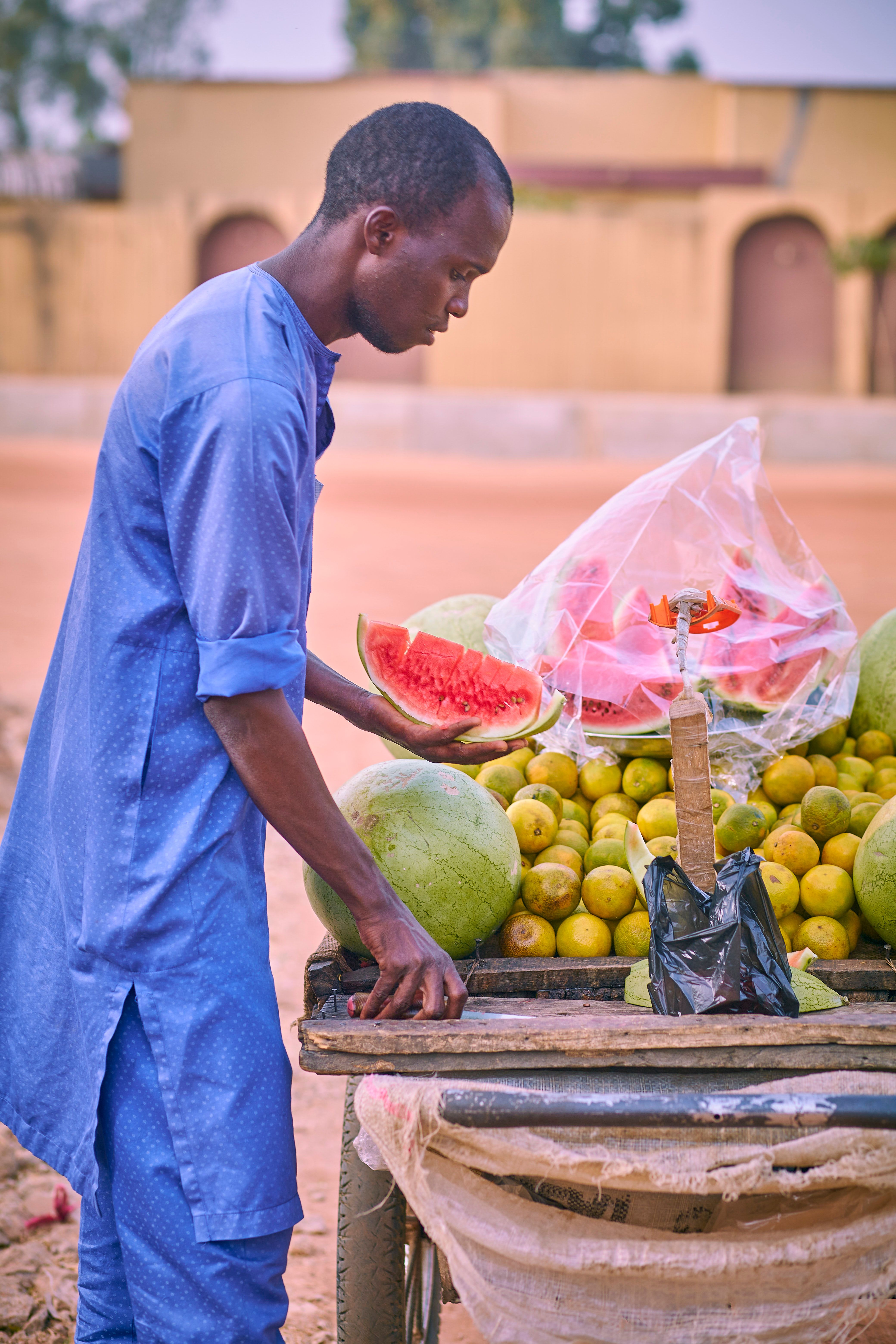 Fruit Vendor Arranging Watermelons and Lemons · Free Stock Photo