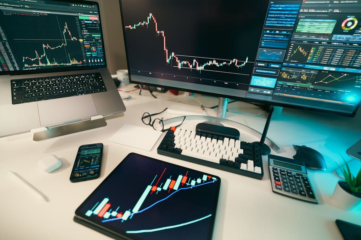 Scrivania di trading con più schermi che mostrano grafici finanziari