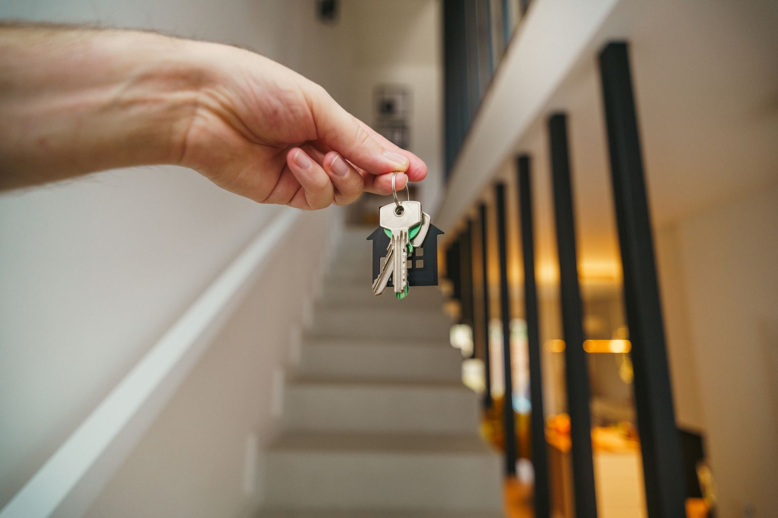 Free A hand holding house keys in a modern interior, symbolizing new home ownership or real estate investment. Stock Photo