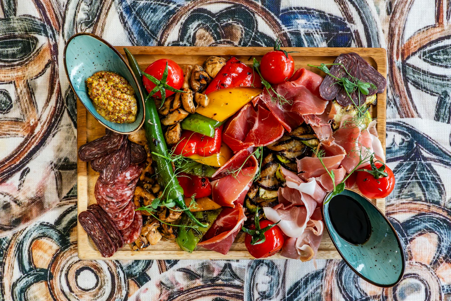 Colorful charcuterie platter featuring meats, cheeses, vegetables, and sauces, perfect for gourmet gatherings.