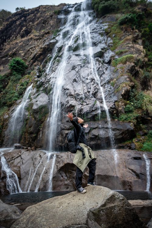 Free A man embraces nature by a stunning waterfall, showcasing adventure and freedom. Stock Photo