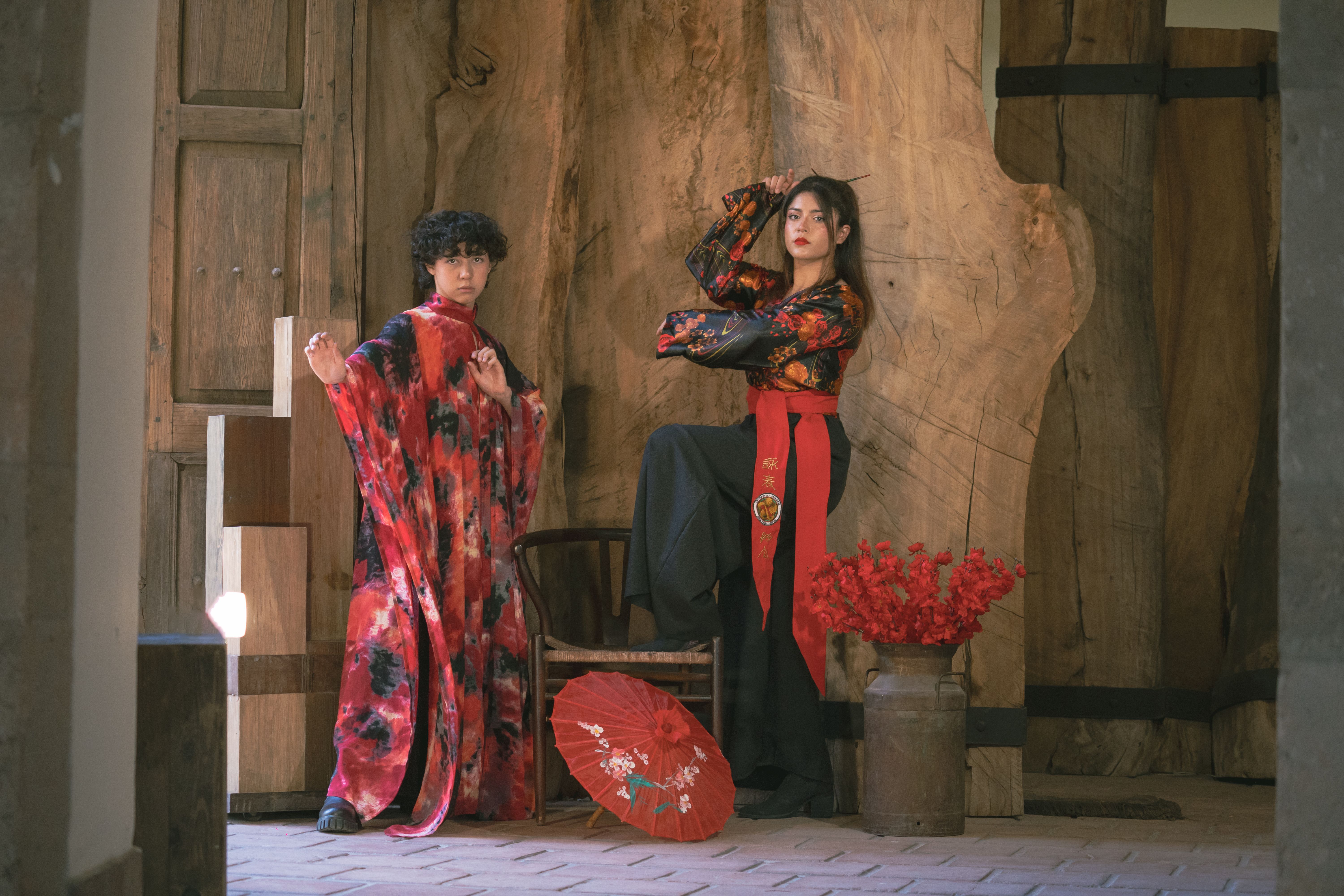 Artistic portrait of two models wearing vibrant kimonos with a rustic wooden backdrop.