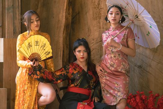 Three women showcasing traditional kimonos and Japanese art, embodying elegance and cultural fashion.