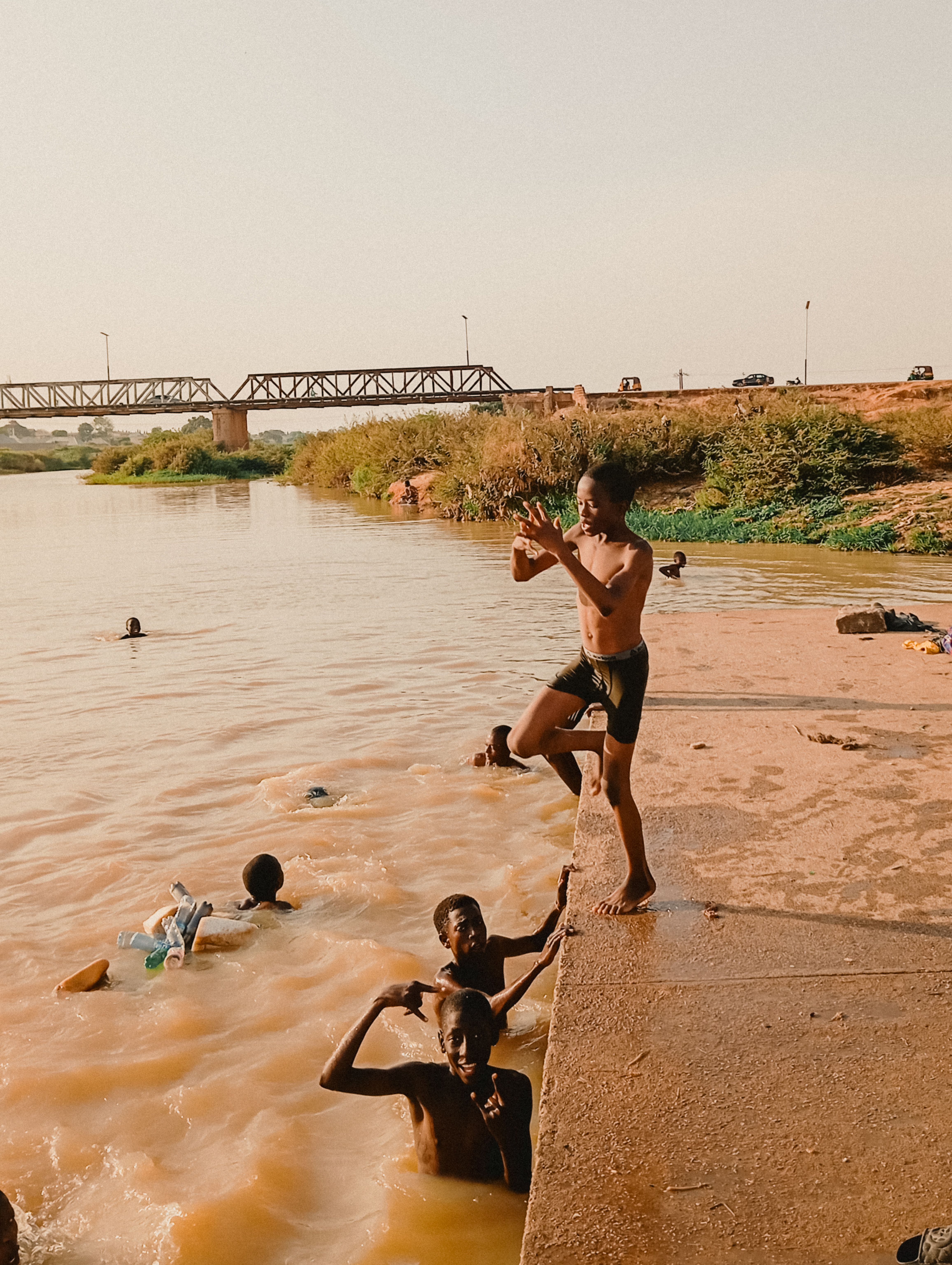 Children playing by a riverside with bridge, Burkina Faso