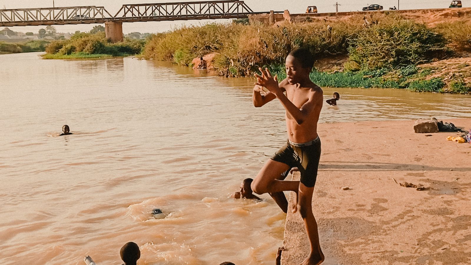 Children playing by a riverside with bridge, Burkina Faso