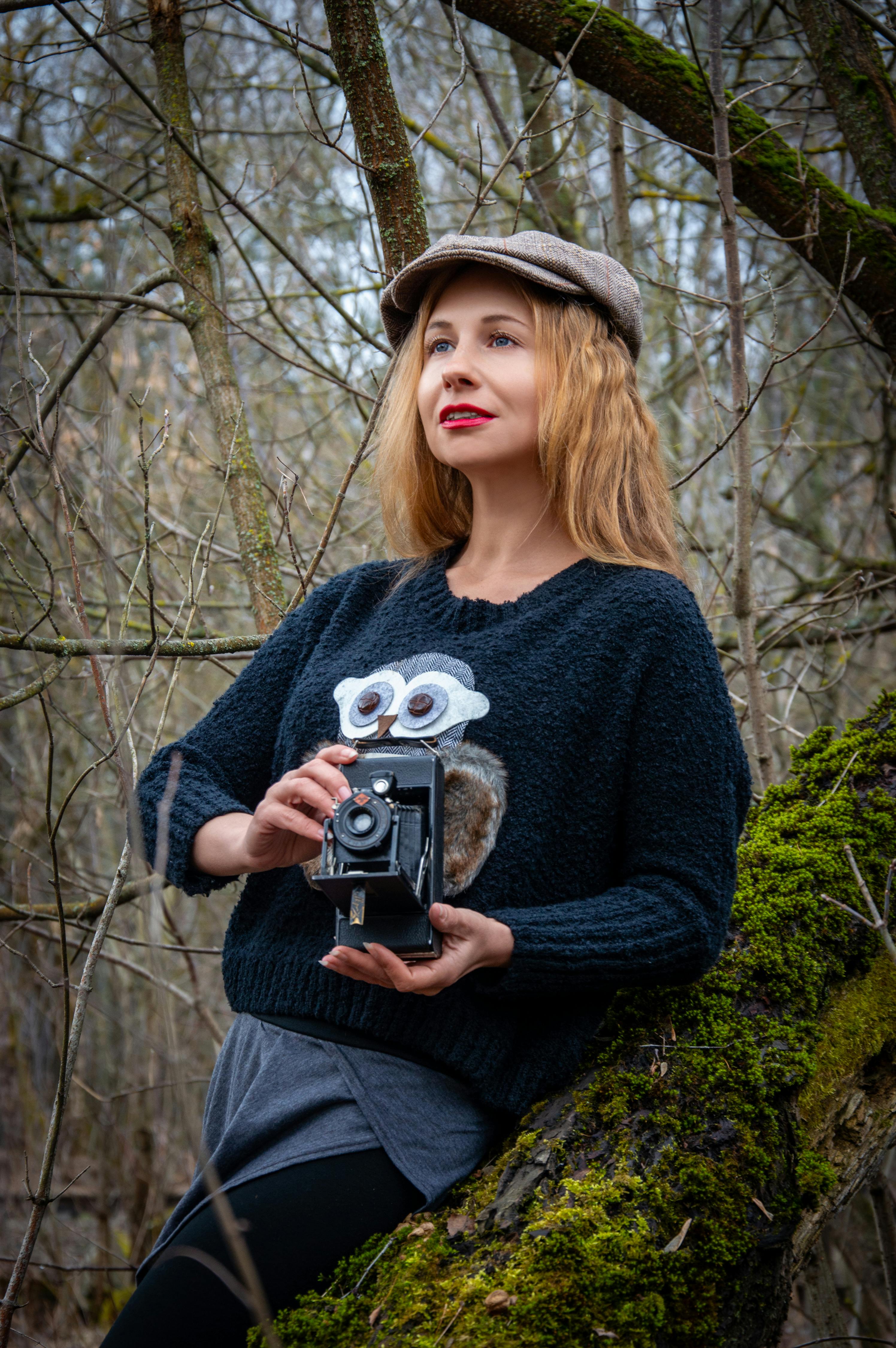 Woman with a retro camera in a forest setting, showing vintage and artistic style.