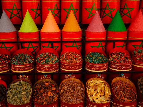 Vibrant display of traditional spices in Moroccan market with colorful cones and aromatic herbs.