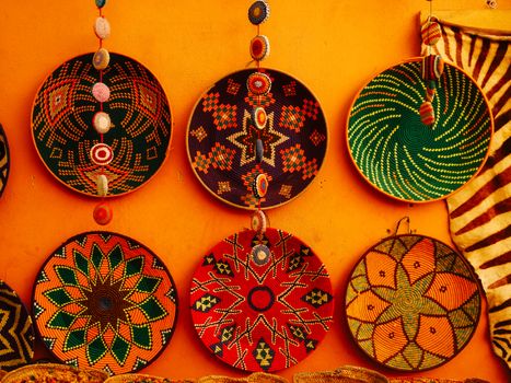 Colorful traditional woven baskets on orange wall showcasing intricate geometric patterns.