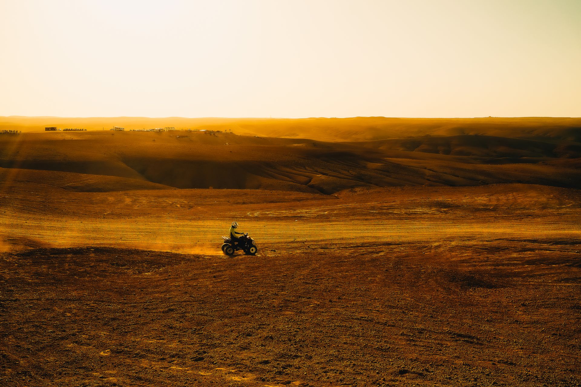 An ATV rider explores a wide open desert under a golden sunset, showcasing adventure and thrill.