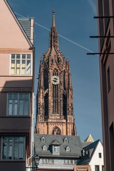 View of the Frankfurter Dom framed by modern buildings on a sunny day in Frankfurt.