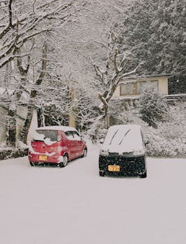 Two snow-covered cars parked on a quiet street in Nikko, Tochigi during winter.