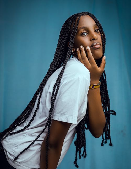 Free Elegant portrait of a woman in a white shirt posing against a blue backdrop. Stock Photo