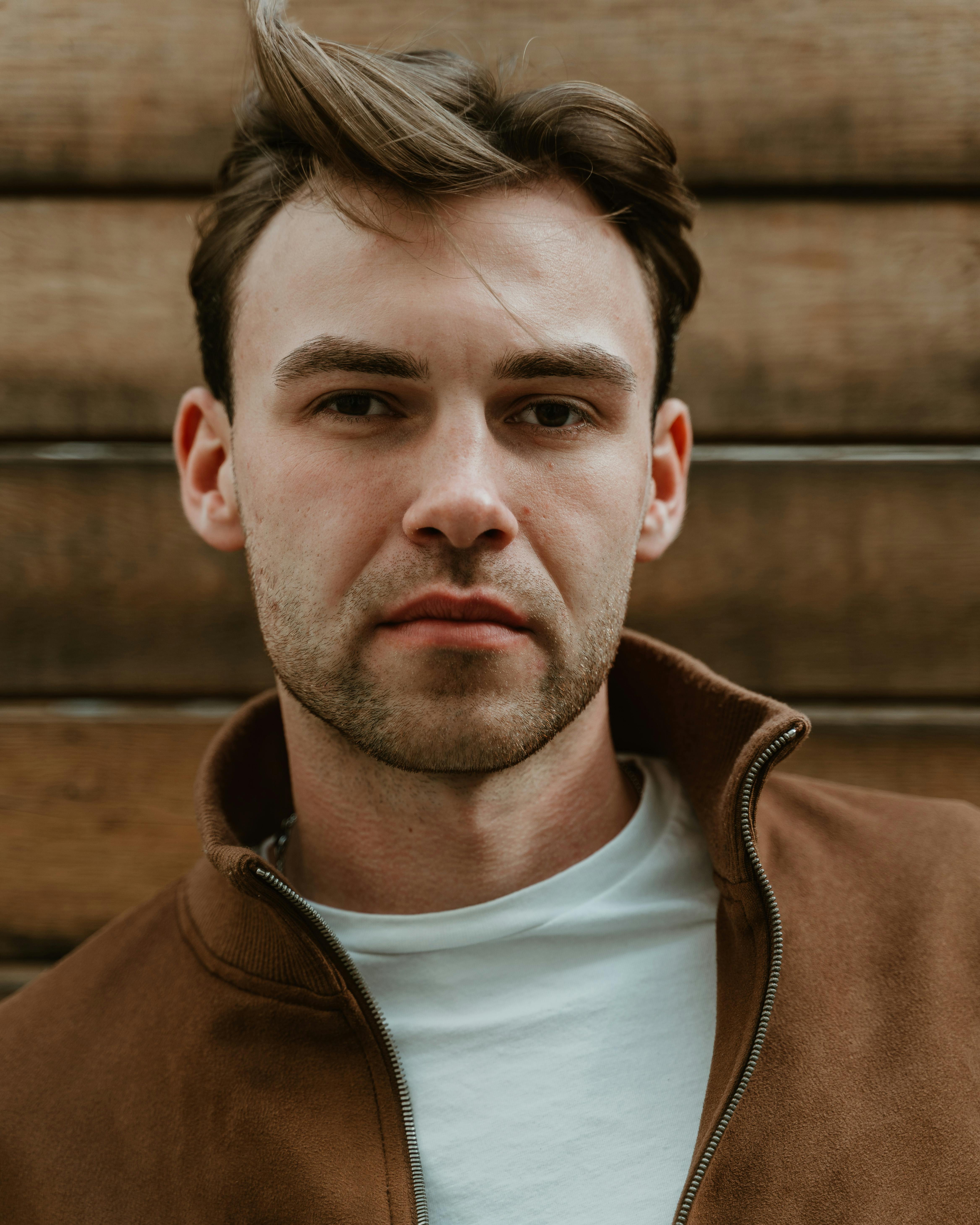 A portrait of a man in a brown jacket, captured outdoors in Berlin, showcasing a relaxed and thoughtful expression.