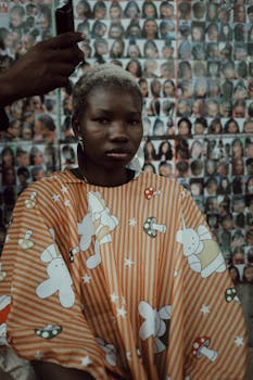 Young person in a barber shop covered with a whimsical cape.
