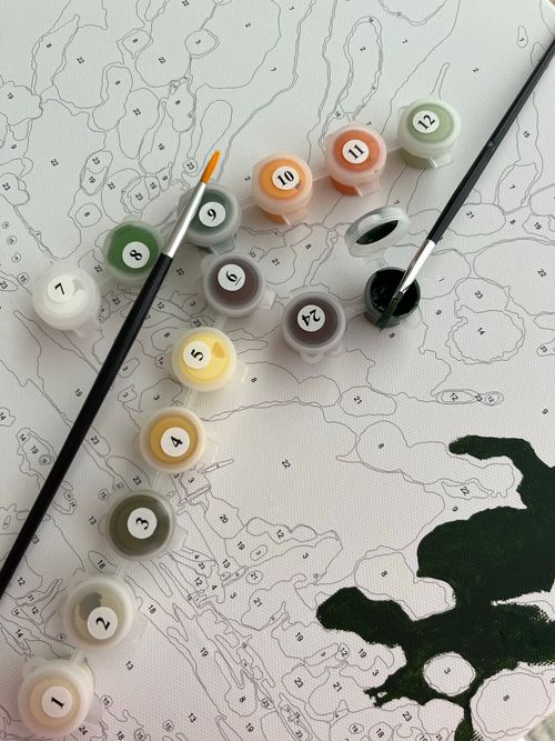 Free Close-up of a paint by numbers canvas with color pots and brushes. Stock Photo