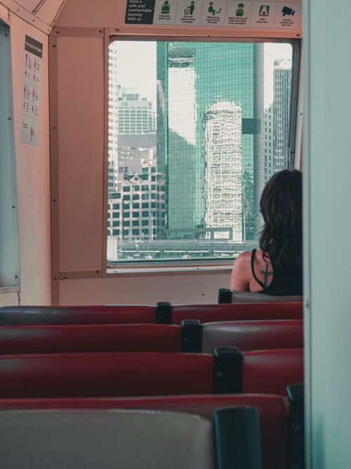 Free Woman on city tram observing skyscrapers through window, modern urban travel. Stock Photo