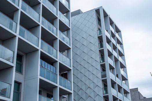 Contemporary glass facade of a city apartment building under a cloudy sky.
