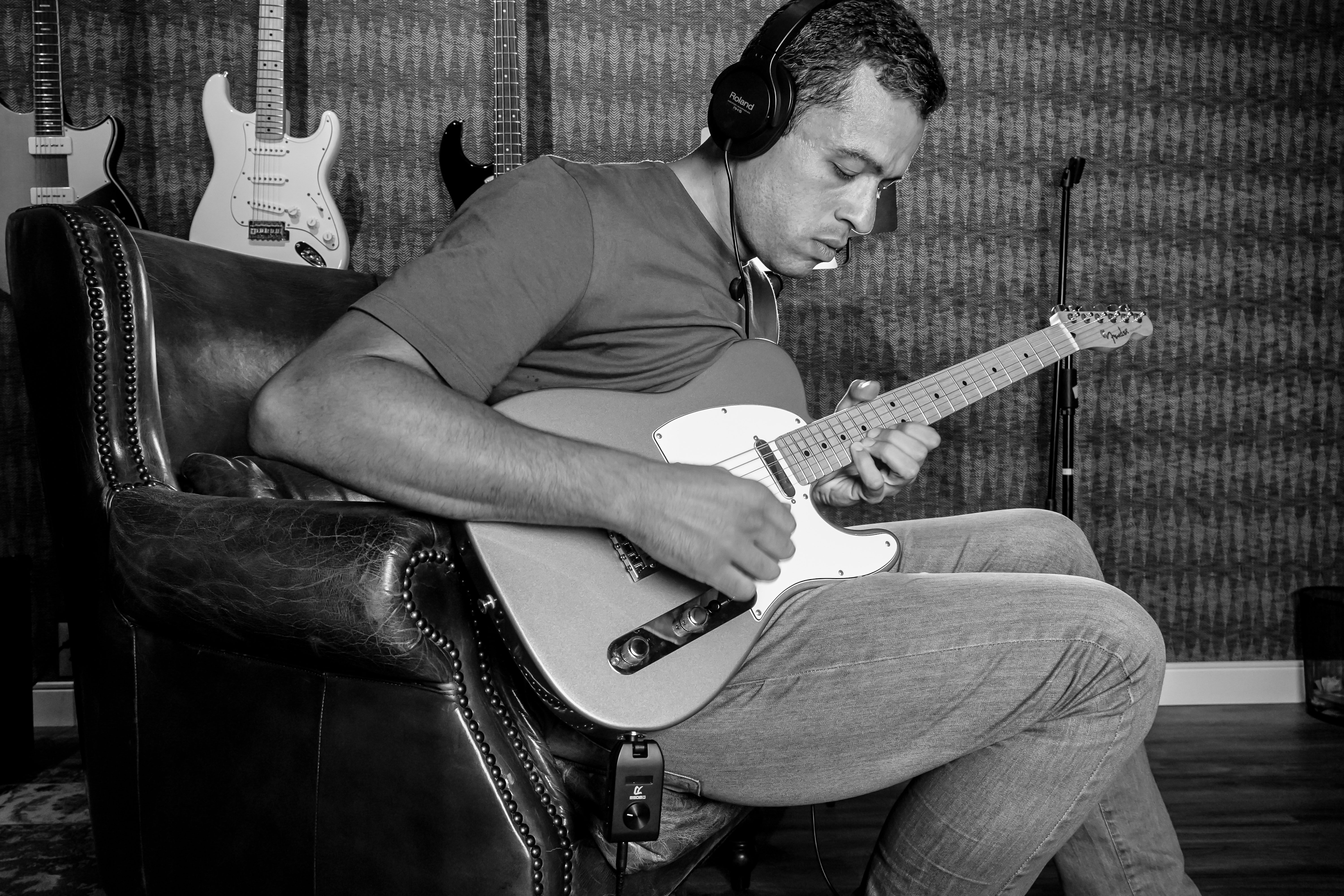 Musician playing electric guitar with headphones in a recording studio