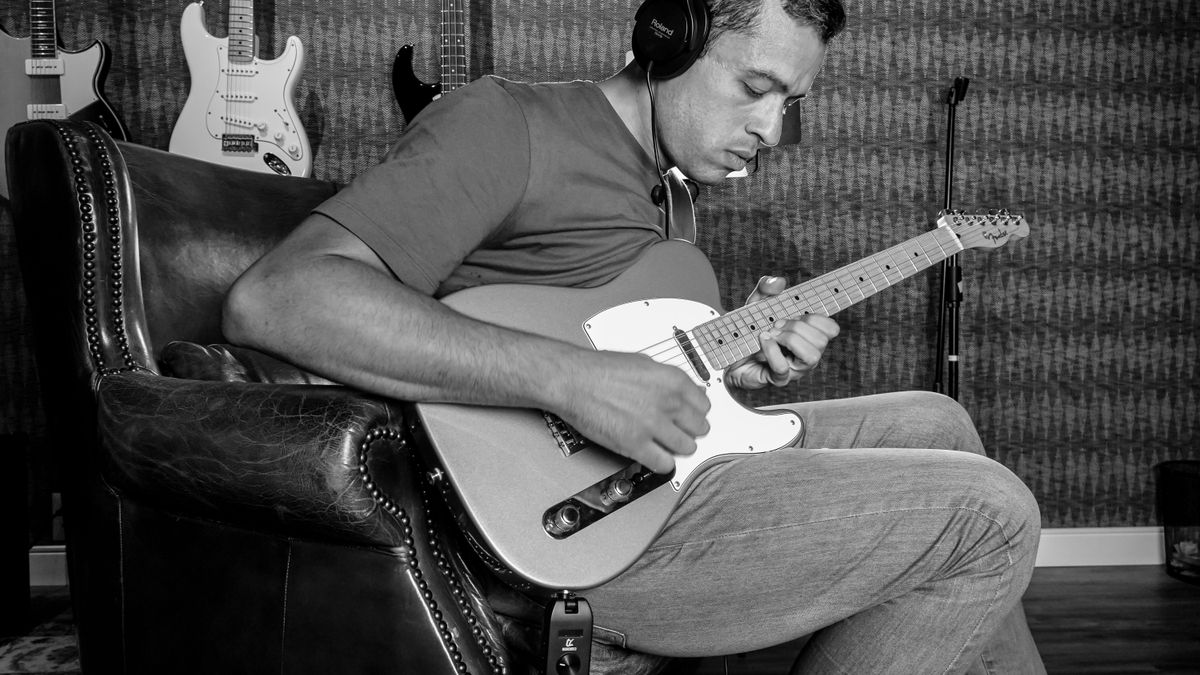 Musician playing electric guitar with headphones in a recording studio
