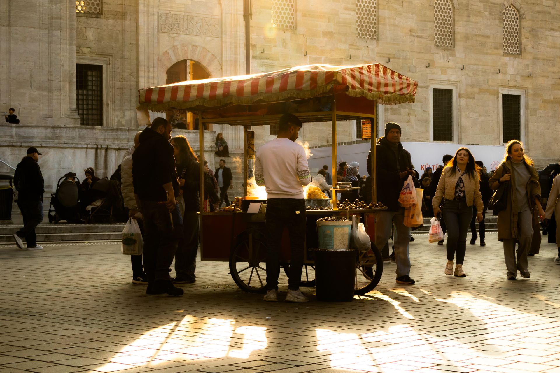 A bustling street scene in Istanbul featuring a chestnut vendor at sunset.