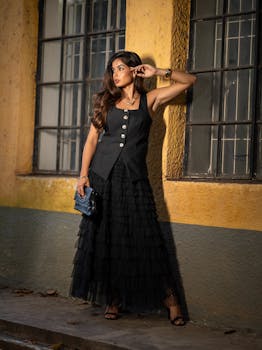 Chic fashion shot of a woman in a black dress with rustic yellow background, São Paulo.