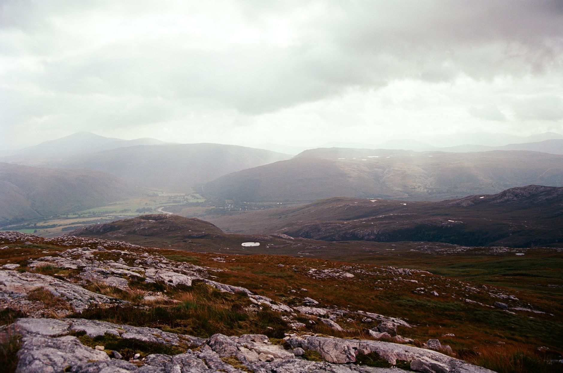 A breathtaking view of the serene Scottish Highlands, showcasing rugged terrain and moody skies.