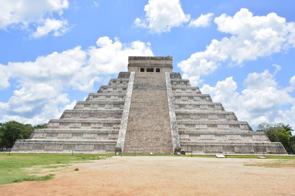 cancun chichen itza private tour - Stunning view of the ancient Pyramid of Chichén Itzá with a bright blue sky and clouds.