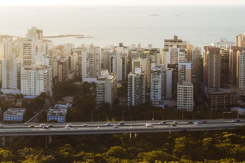 Free High-rise buildings overlooking the ocean with a highway, captured during sunset, in a coastal city. Stock Photo