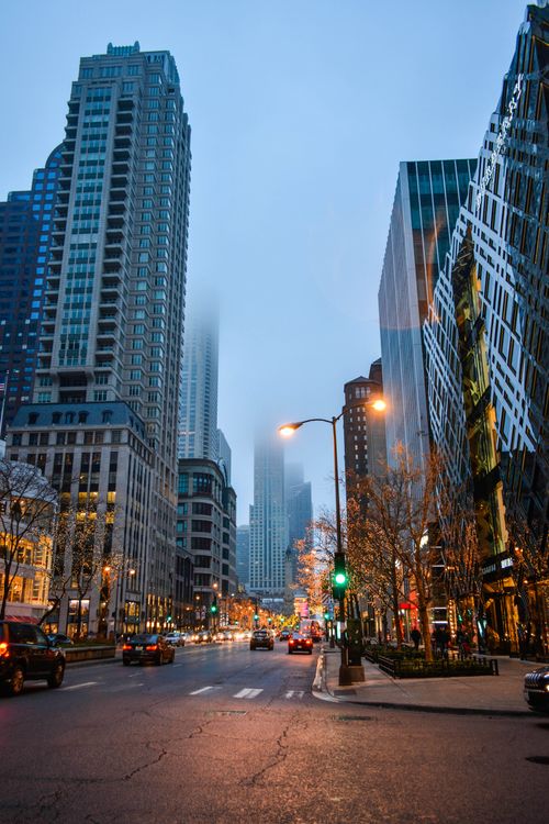 Free Evening view of a busy downtown Chicago street surrounded by skyscrapers on a foggy night. Stock Photo