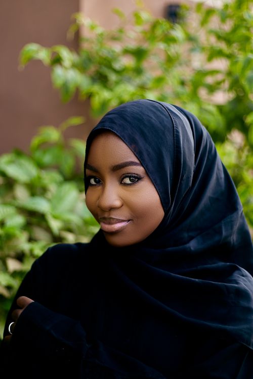 Free Elegant portrait of a woman in black hijab with greenery in the background, radiating confidence. Stock Photo