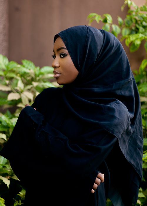 Free Elegant profile of a woman in black hijab against lush green backdrop. Stock Photo