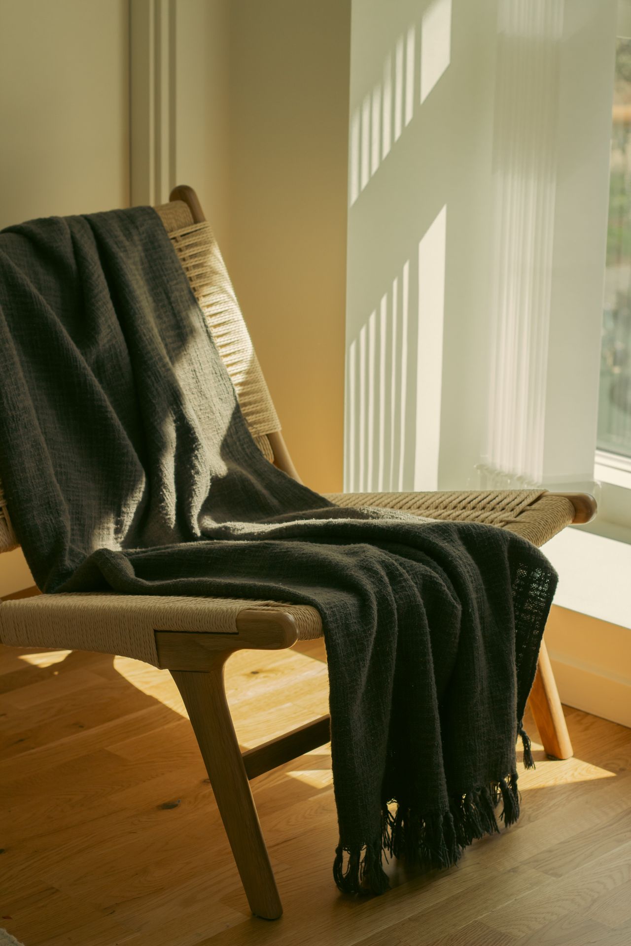 Dark throw blanket draped over a sunlit chair