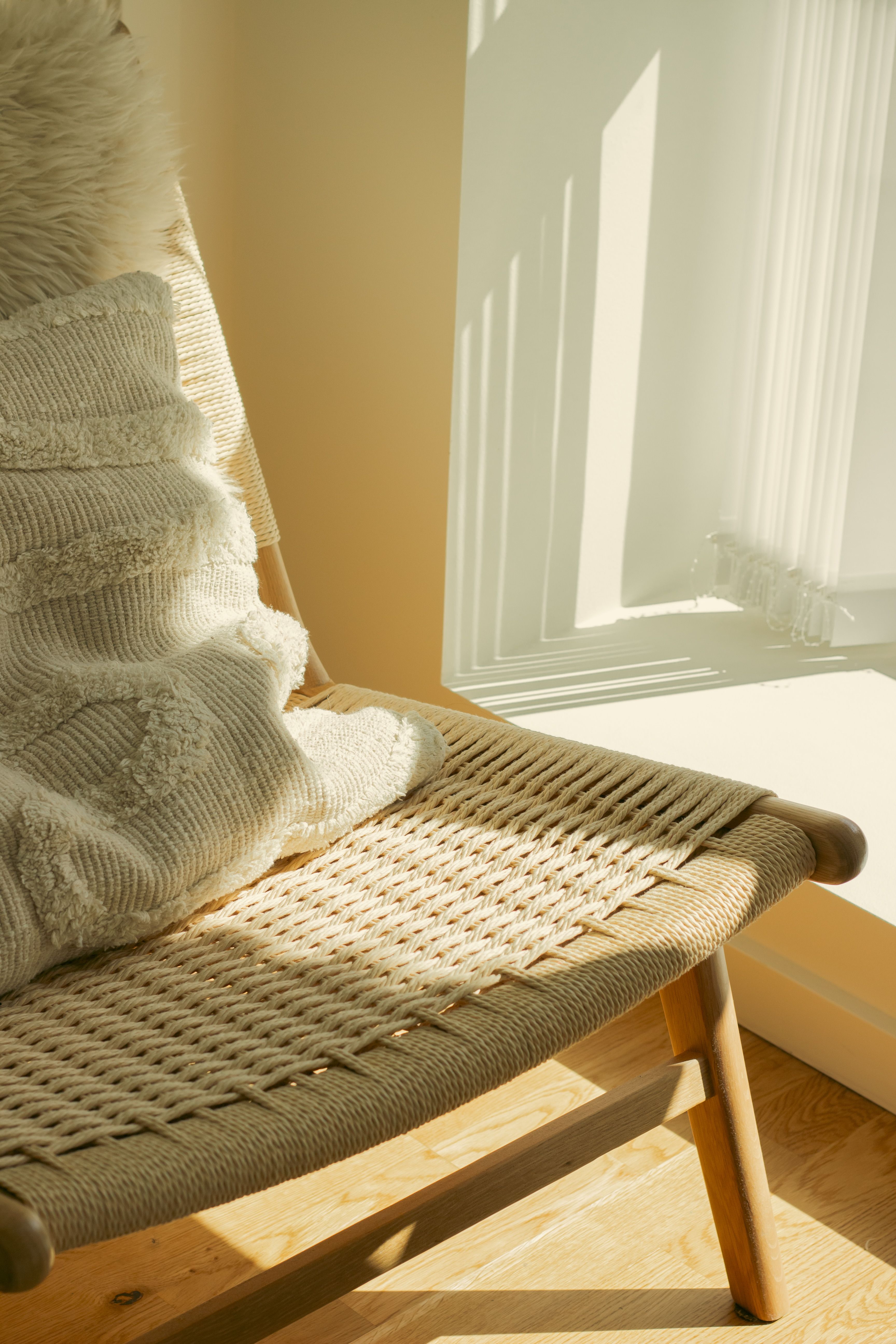 Image showcasing Cozy Sunlit Corner with Woven Chair and Pillow · Free Stock Photo